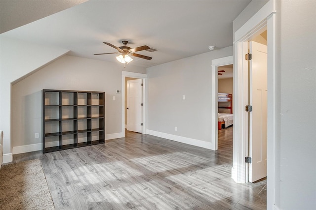additional living space with baseboards, wood finished floors, and ceiling fan
