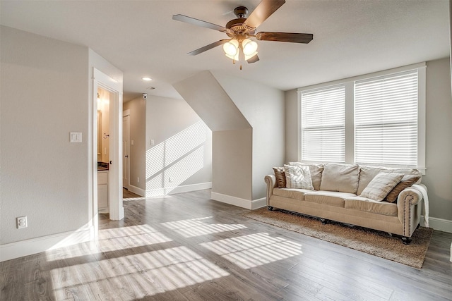 living area featuring baseboards, a ceiling fan, and light wood finished floors