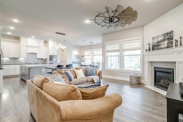 living area featuring baseboards, recessed lighting, wood finished floors, and a tiled fireplace