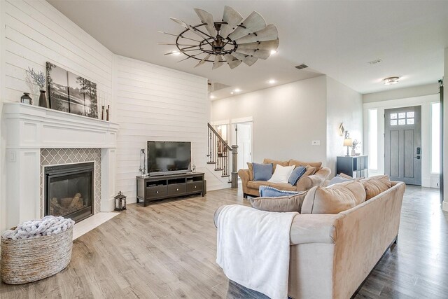 living room featuring recessed lighting, light wood-style floors, visible vents, and a glass covered fireplace