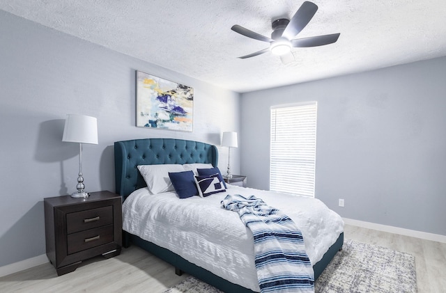 bedroom featuring a textured ceiling, light wood-type flooring, ceiling fan, and baseboards
