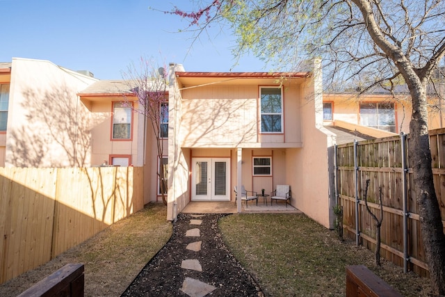 rear view of property featuring french doors, stucco siding, a fenced backyard, and a patio area