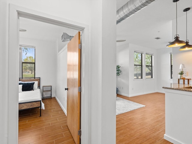 hallway featuring baseboards, visible vents, and light wood-type flooring