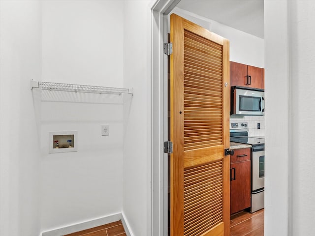 laundry area with baseboards, washer hookup, laundry area, and wood finish floors