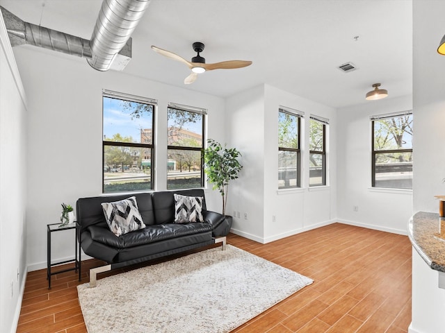 living room with light wood finished floors, a healthy amount of sunlight, visible vents, and a ceiling fan