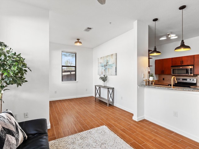 living area with baseboards, visible vents, and wood finished floors