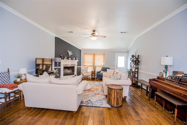 living area featuring a fireplace, a ceiling fan, ornamental molding, visible vents, and wood finished floors