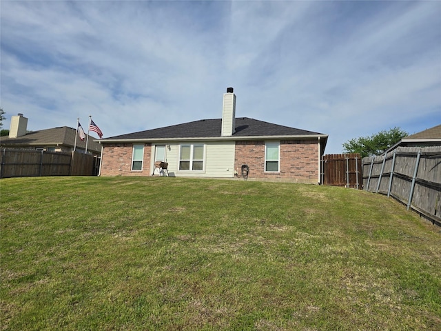 back of property with brick siding, a fenced backyard, and a lawn