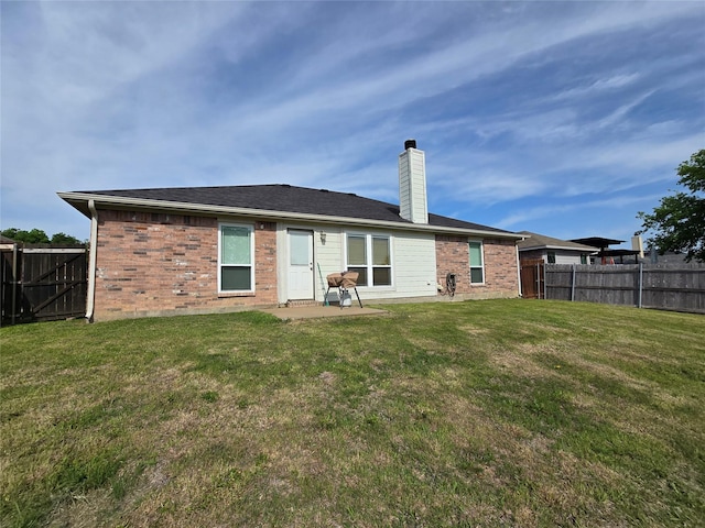 rear view of house featuring a yard, a fenced backyard, brick siding, and a patio