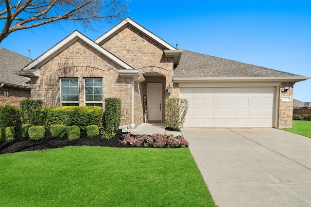 view of front facade with a front yard, concrete driveway, brick siding, a shingled roof, and a garage