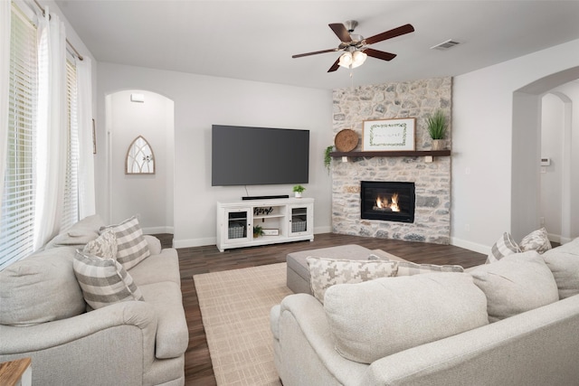 living area featuring a wealth of natural light, visible vents, arched walkways, and a ceiling fan