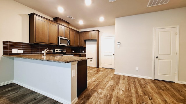 kitchen featuring visible vents, a peninsula, a sink, and stainless steel appliances