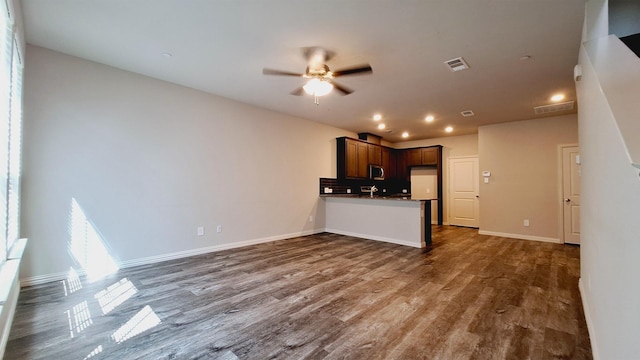 unfurnished living room featuring visible vents, baseboards, ceiling fan, and dark wood finished floors