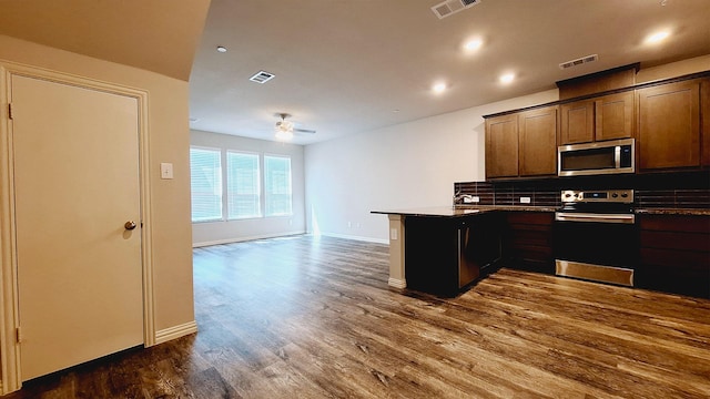kitchen with stainless steel microwave, dark wood-type flooring, electric stove, visible vents, and a peninsula