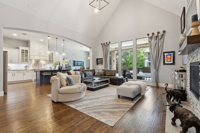 3960 Briar Tree Ln, Frisco, TX 75034 - living room with dark wood-type flooring, a fireplace, high vaulted ceiling, arched walkways, and recessed lighting