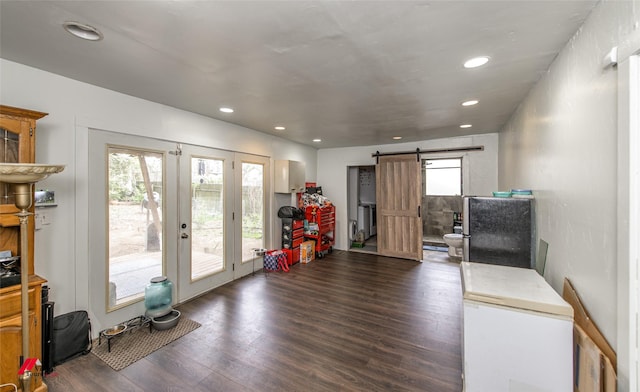 interior space with a wealth of natural light, a barn door, french doors, and dark wood finished floors