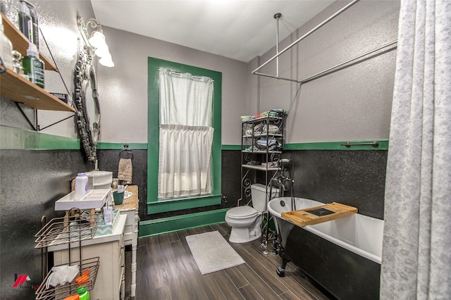 full bathroom with a freestanding tub, wood finished floors, and toilet
