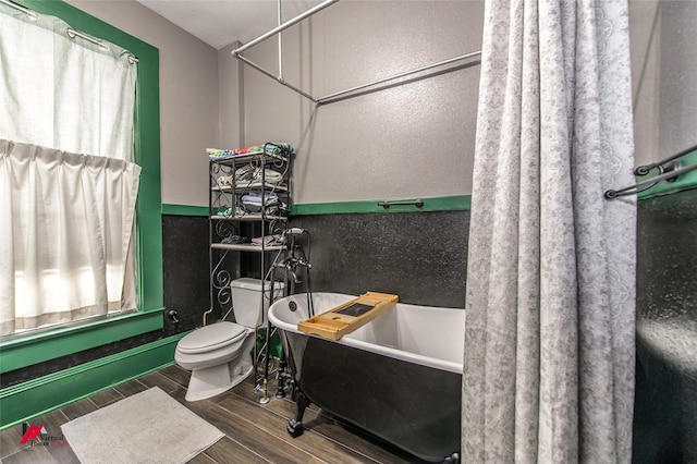 bathroom featuring a freestanding tub, wood finished floors, and toilet