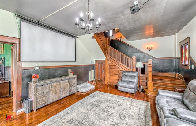 cinema featuring wood finished floors, a wainscoted wall, and a chandelier