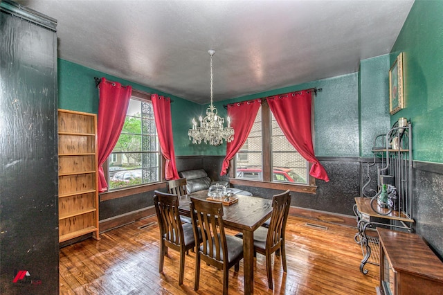 dining area featuring an inviting chandelier, visible vents, hardwood / wood-style floors, and baseboards