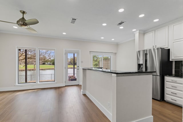 kitchen with crown molding, stainless steel fridge with ice dispenser, white cabinetry, visible vents, and baseboards