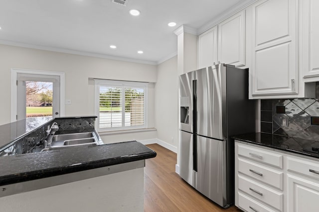 kitchen with ornamental molding, white cabinets, stainless steel refrigerator with ice dispenser, wood finished floors, and a sink