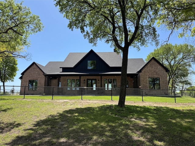 view of front of home with a front yard, fence, and brick siding