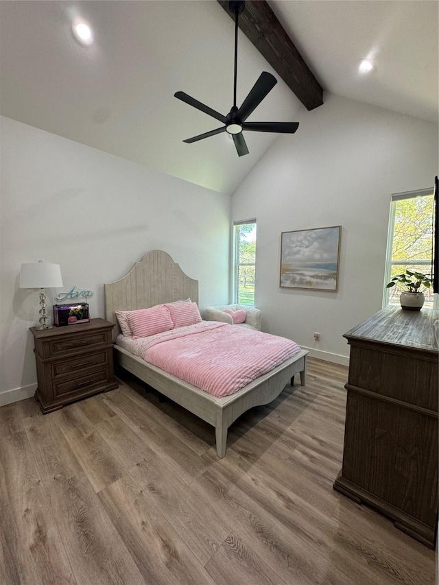 bedroom with wood finished floors, baseboards, multiple windows, and beam ceiling