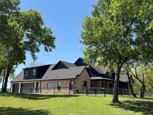 exterior space featuring a garage, a lawn, board and batten siding, fence, and brick siding