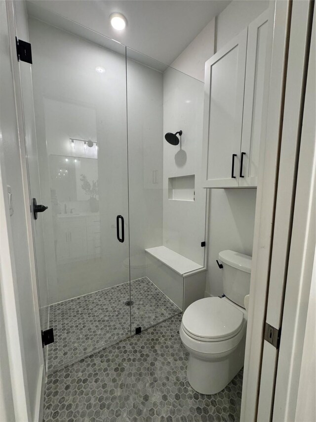 bathroom with a shower stall, tile patterned flooring, and toilet