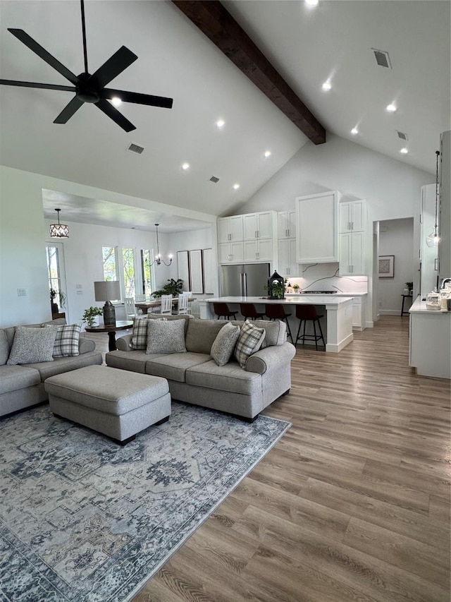 living room with light wood finished floors, high vaulted ceiling, beamed ceiling, and visible vents