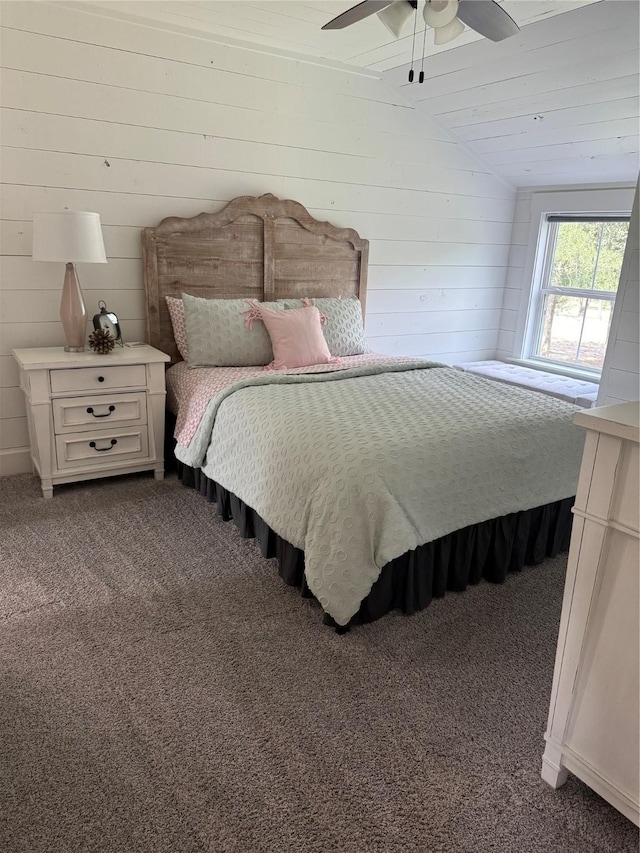 bedroom with wood walls, ceiling fan, dark colored carpet, and vaulted ceiling
