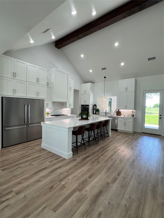 kitchen featuring beamed ceiling, white cabinetry, visible vents, appliances with stainless steel finishes, and light countertops