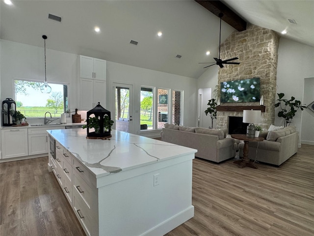 kitchen featuring white cabinets, a ceiling fan, visible vents, and a wealth of natural light