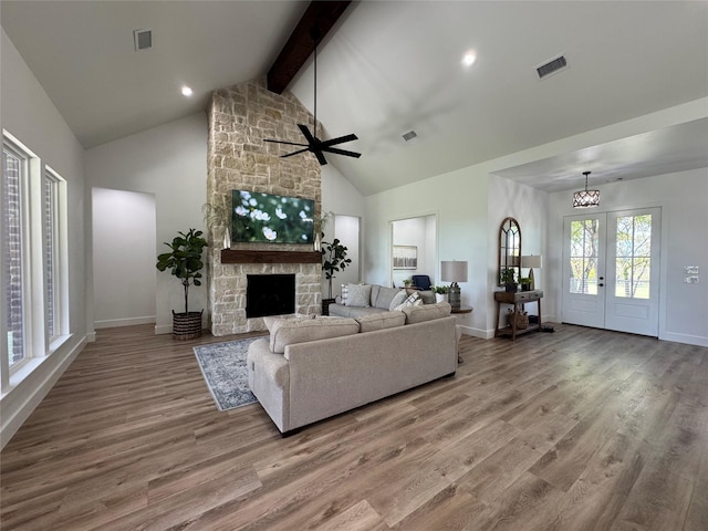 living room with visible vents, a stone fireplace, and wood finished floors
