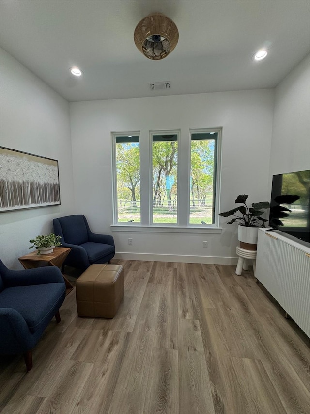 living area featuring radiator heating unit, visible vents, baseboards, and wood finished floors