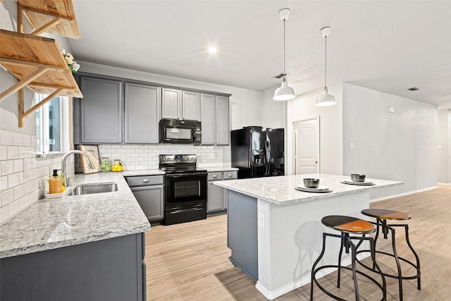 9173 Blackstone Dr, Providence Village, TX 76227 - kitchen featuring black appliances, a sink, gray cabinetry, and a center island
