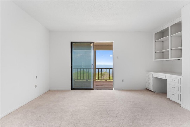 3709 Windmill Hill St, Waco, TX 76710 - unfurnished room featuring light colored carpet, built in desk, baseboards, and a textured ceiling