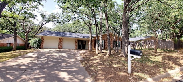 view of front of house with an attached garage, fence, concrete driveway, and brick siding