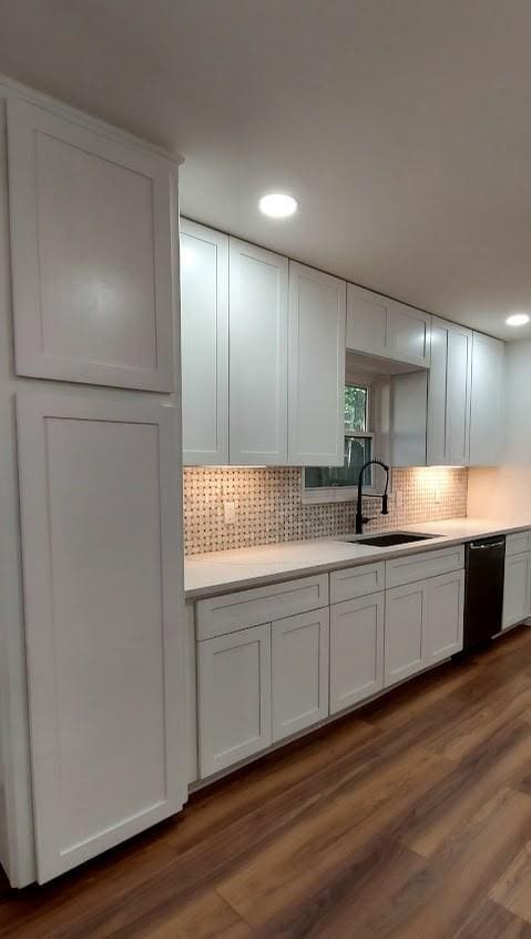 kitchen featuring light countertops, black dishwasher, a sink, and white cabinets