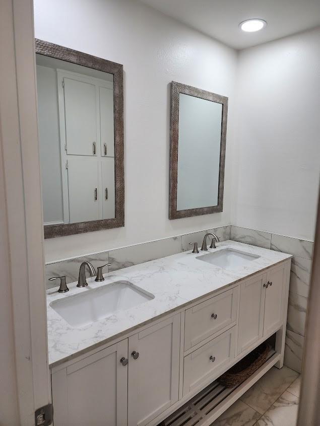 bathroom with marble finish floor, a sink, and double vanity
