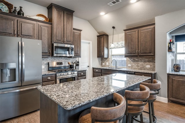 1001 Hodge St, Mckinney, TX 75071 - kitchen featuring appliances with stainless steel finishes, a sink, dark brown cabinetry, a center island, and vaulted ceiling
