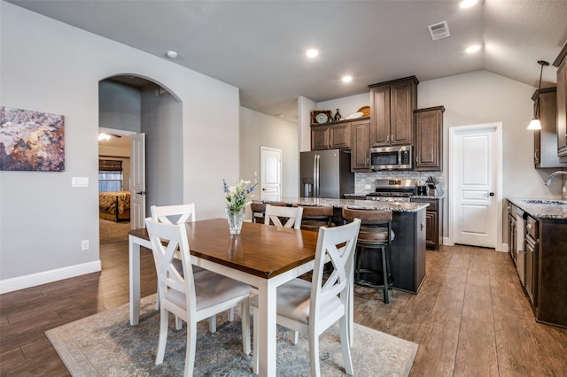 1001 Hodge St, Mckinney, TX 75071 - dining room featuring wood-type flooring, arched walkways, vaulted ceiling, and baseboards