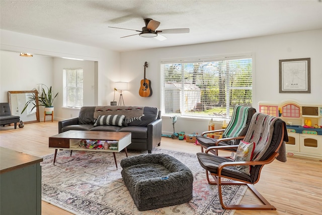 living area with light wood-style floors, a healthy amount of sunlight, ceiling fan, and a textured ceiling