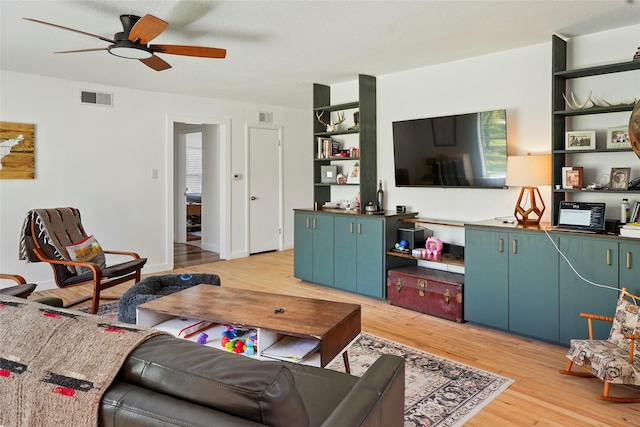 living area featuring light wood-style floors, visible vents, and ceiling fan