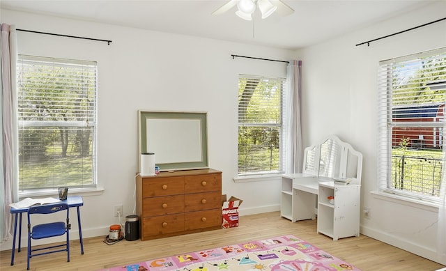recreation room featuring ceiling fan, a wealth of natural light, wood finished floors, and baseboards