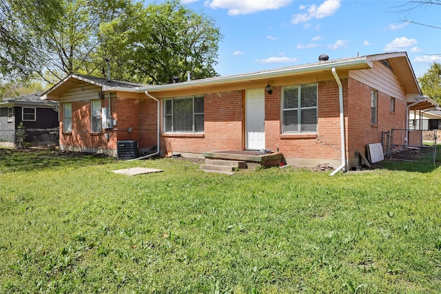 view of front facade featuring brick siding, a front lawn, fence, and cooling unit