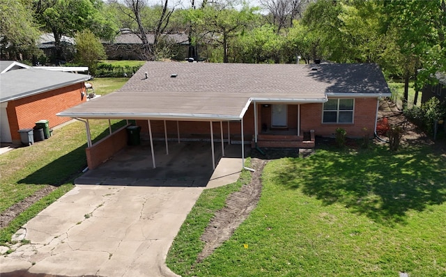 ranch-style home with concrete driveway, brick siding, a front lawn, an attached carport, and roof with shingles