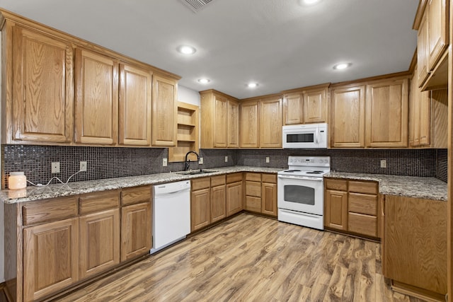 kitchen with light wood-style flooring, a sink, tasteful backsplash, and white appliances