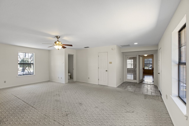 unfurnished room featuring baseboards, carpet flooring, visible vents, and a ceiling fan